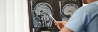 Neurosurgeon explains image of brainscan using pen as pointer.